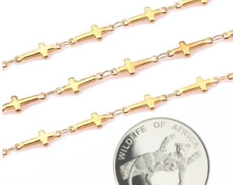 May include: Three gold chains with small cross charms. The chains are layered on top of each other. A silver coin with the words "Wildlife of Africa" and "500 Nouveaux Zaires" is in the bottom right corner of the image.