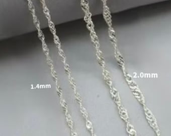 May include: Four silver chains of different thicknesses, labelled 1.4mm and 2.0mm. The chains are laid out in a row, with the thickest chain on the right and the thinnest chain on the left.