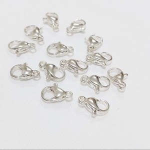 Peut inclure: Un groupe de 15 fermoirs à ressort en argent. Ces fermoirs sont couramment utilisés pour la fabrication de bijoux et l'artisanat.