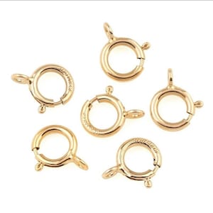 Peut inclure: Six fermoirs à ressort en métal doré, chacun avec un anneau rond et une fermeture à ressort. Les fermoirs sont couramment utilisés pour la fabrication de bijoux.