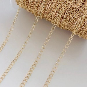 Peut inclure: Chaîne dorée avec un design délicat et lié. La chaîne est enroulée autour d'une bobine et plusieurs brins pendent.