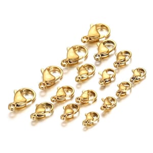 May include: A set of 15 gold-toned lobster clasps of varying sizes. The clasps are made of metal and have a polished finish.