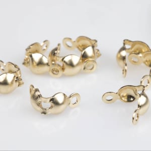 May include: Five gold-toned metal clasps for jewellery making. Each clasp has a rounded shape and a hinged design.