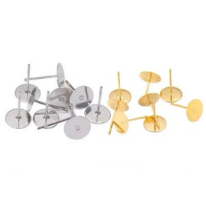 May include: A close-up of earring findings, with a mix of silver and gold-toned metal. The findings are round and have a small hole in the centre. They are used to attach earrings to a post.