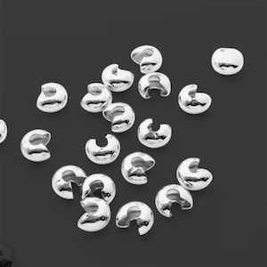 May include: A group of silver-toned metal crimp beads, used for jewellery making.