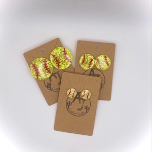 May include: Three pairs of yellow and red softball earrings on brown cards with the text "Custom Crafts".