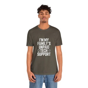 May include: An olive green t-shirt with the white text "I'M MY FAMILY'S UNPAID TECH SUPPORT". The design includes a computer monitor and a gear symbol. The shirt is made of a soft material.
