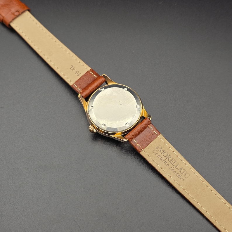 May include: A gold-toned wristwatch with a brown leather band. The watch face is visible, and the band is marked "MORELLATO Genuine leather". The band is a size 16 XL.
