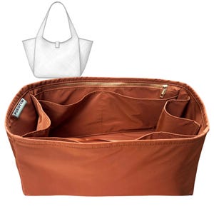 May include: A rust-colored tote bag organizer with multiple compartments and a zippered top. The organizer has a rectangular shape and is designed to fit inside a larger tote bag. A white tote bag illustration is in the upper left corner.