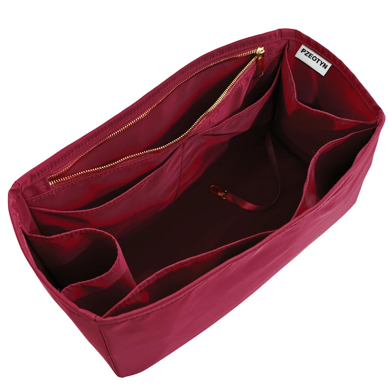 May include: A burgundy handbag organizer with multiple compartments and a zippered pocket. The organizer has a gold zipper and a small tag that reads "PZEOTYN". The interior is a darker shade of burgundy.