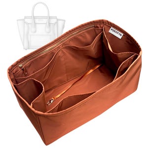 Pode incluir: Um organizador de bolsa cor de ferrugem com vários compartimentos e fecho de correr. O organizador tem um pequeno fecho de metal e uma etiqueta que diz "PZEOTYN". Uma bolsa transparente está no fundo.