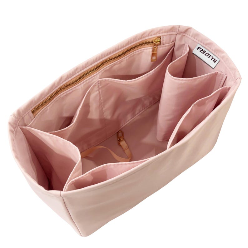 May include: A light pink handbag organizer with multiple compartments and a gold zipper. The organizer has several pockets of varying sizes and a small strap with a gold clasp. The brand name "PZEOTYN" is visible on a white tag.