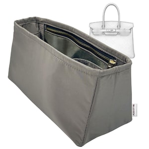 Könnte beinhalten: Ein grauer Handtaschen-Organizer mit mehreren Fächern und einem Reißverschluss. Der Organizer besteht aus einem glatten, strapazierfähigen Material und verfügt über einen goldfarbenen Reißverschluss. Eine Skizze einer Handtasche befindet sich im Hintergrund.