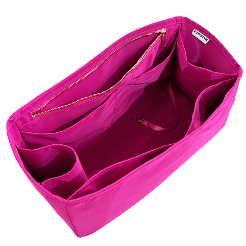 May include: A bright pink bag organizer with multiple compartments and a zippered closure. The interior features various pockets and a small strap with a clasp. The organizer is designed to fit inside a larger bag, providing organization and easy access to items.