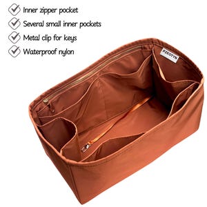 May include: A rust-colored nylon bag organizer with multiple compartments and a metal key clip. Features include an inner zipper pocket and several small inner pockets. The text on the image indicates the organizer is made of waterproof nylon.