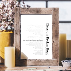 Puede incluir: Una impresión enmarcada de la letra de la canción "Bless the Broken Road" de Rascal Flatts. La letra está impresa en tinta negra sobre un fondo blanco. El marco es de madera rústica.