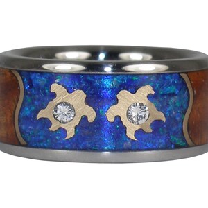 May include: A titanium ring with a blue and brown inlay featuring two gold sea turtles with diamonds in their centres.