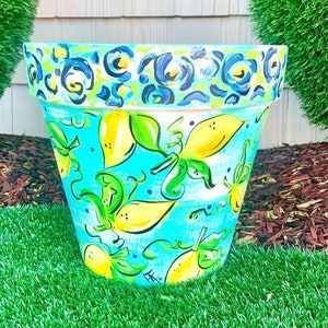 May include: A blue and white ceramic planter with a yellow lemon design. The planter has a blue and white floral pattern around the top rim.