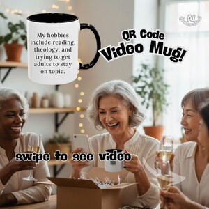 May include: A white ceramic mug with a black handle and interior, featuring the black text: My hobbies include reading, theology, and trying to get adults to stay on topic. The mug is displayed alongside text reading QR Code Video Mug.