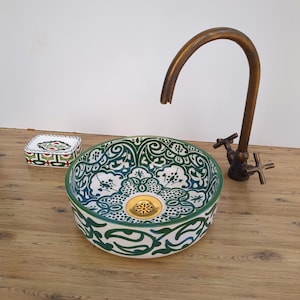 Może przedstawiać: Zestaw trzech ceramicznych misek w odcieniach niebieskiego, zielonego i białego. Miski mają nakrapianą glazurę i prosty, nowoczesny design. Największa miska ma średnicę około 15 cm.