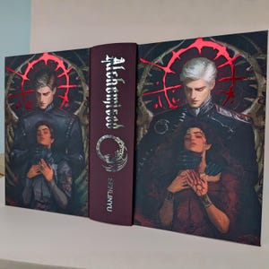 May include: A hardcover book with a burgundy spine and cover art featuring two figures. The title "Alchemist" is displayed vertically in silver lettering. The cover art depicts a man and woman in a dramatic pose, with a red, circular design.