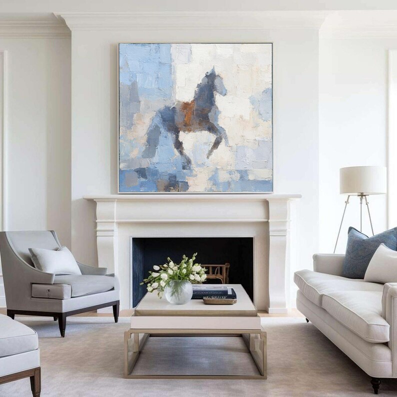 May include: Abstract painting of a horse in blue, grey, and brown tones. The artwork is displayed above a white fireplace in a living room. The framed painting adds a touch of elegance to the room. The room has a sofa and chairs.