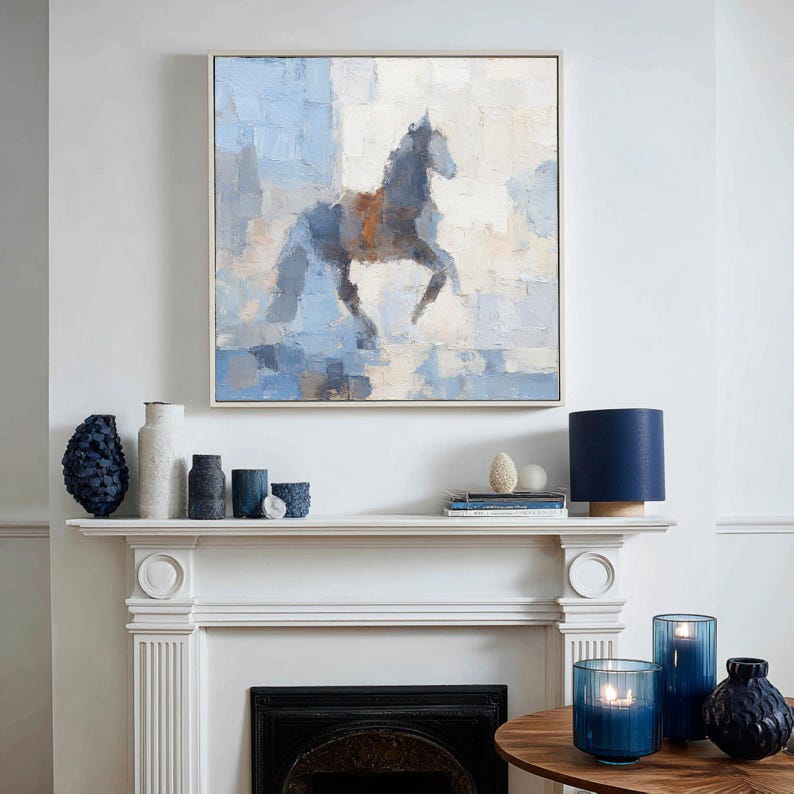 May include: An abstract painting of a horse in shades of blue and brown hangs above a white mantelpiece. The artwork is framed in a light-coloured wood. Decorative vases, candles, and a lamp in shades of blue adorn the mantelpiece and a nearby table.