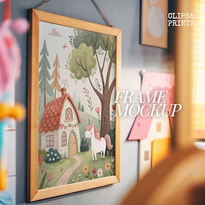 May include: A framed illustration of a whimsical cottage in a woodland setting with a unicorn standing in front of it. The cottage has a red roof and white walls, and the woodland is filled with green trees and flowers. The unicorn is white with a pink mane and tail. The frame is made of wood and has a light brown finish. The text "FRAME MOCKUP" is visible in the image.