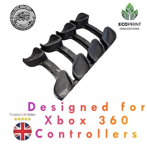 May include: Four black plastic moulds designed for Xbox 360 controllers. The moulds are arranged in a row, with each mould featuring a unique shape.