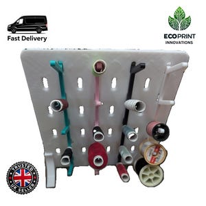 May include: White plastic thread organizer with multiple slots and pegs for storing spools of thread. The organizer has a variety of colored threads in the slots and pegs.