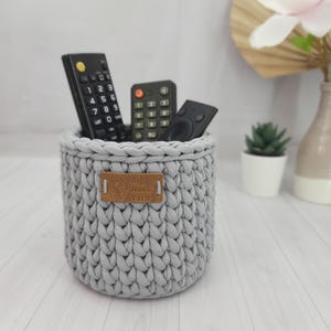 Puede incluir: Una taza de cerámica blanca con un asa negra y el texto "But First, Coffee" en negrita negra. La taza está sobre una superficie de madera. La taza mide aproximadamente 10 cm de alto.