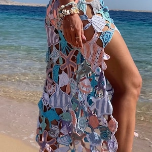 May include: A crochet skirt with a sea-life design. The skirt is made of a variety of colors, including blue, green, pink, and white. The skirt features a variety of sea creatures, including starfish, seashells, and fish.