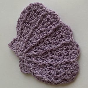 Op de afbeelding: Een handgemaakte, lavendelkleurige gehaakte onderzetter met een geschulpte rand. De onderzetter heeft een textuur, open geweven ontwerp, dat het ingewikkelde stikselwerk laat zien. Ideaal voor warme of koude dranken.