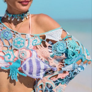 May include: A crocheted off-the-shoulder top with a floral and seashell design in shades of blue, pink, and white.