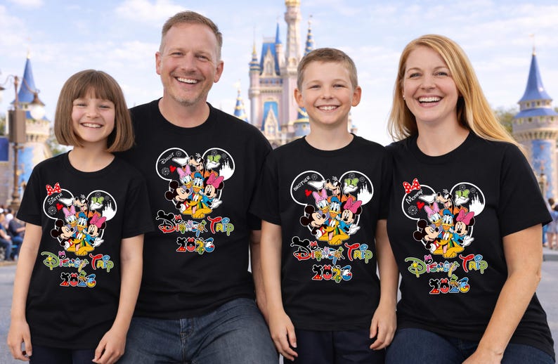 May include: Four people wearing matching black t-shirts with a colourful Disney character design and the text "Disney Trip 2023". The shirts feature Mickey Mouse ears and various Disney characters.