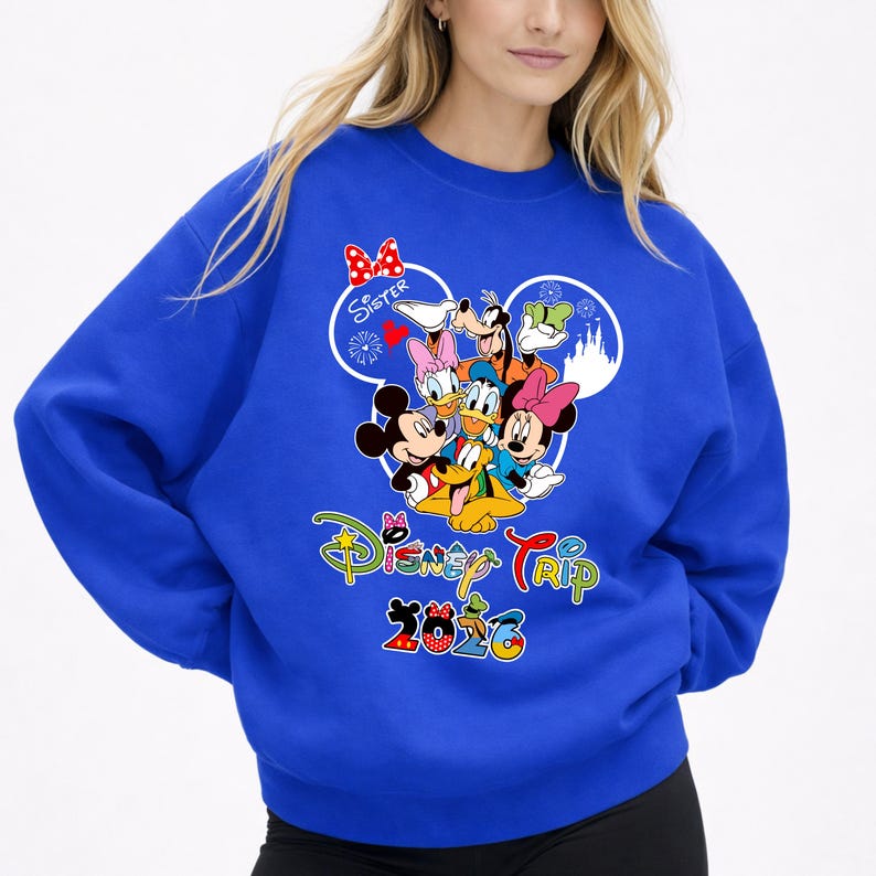 May include: Royal blue sweatshirt with a Disney Trip 2023 graphic. The design features Mickey Mouse, Minnie Mouse, Donald Duck, Goofy, and Daisy Duck. The word "Sister" is above the characters in a heart-shaped design.