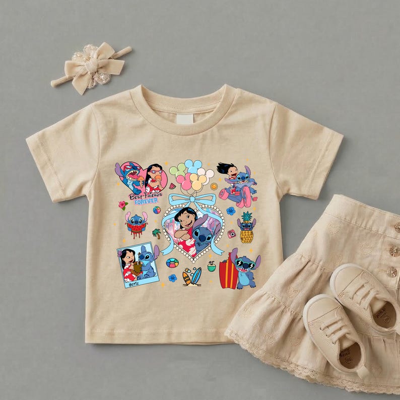 May include: A beige short-sleeved t-shirt featuring a colorful graphic print of Lilo and Stitch characters, including the text Best Friends Forever, accompanied by a matching beige hair bow, a beige tiered skirt, and beige sneakers.