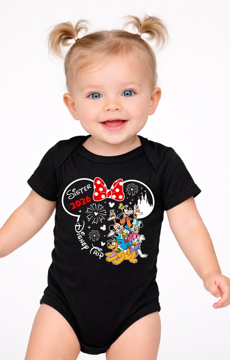 May include: A smiling baby wearing a black bodysuit with a Minnie Mouse-themed design. The design includes a red polka-dot bow, the words "Sister 2026", and Disney characters. The bodysuit is short-sleeved.