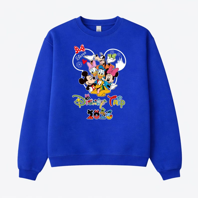 May include: A royal blue sweatshirt with a colourful graphic of Disney characters, including Mickey and Minnie Mouse, Donald Duck, and Goofy. The text "Disney Trip 2023" is displayed in a vibrant, multi-coloured font. A red bow is visible.