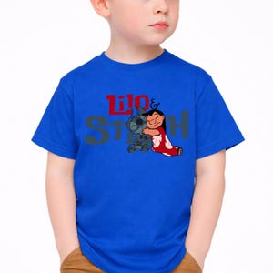 K&ouml;nnte beinhalten: Ein leuchtend blaues T-Shirt mit kurzen &Auml;rmeln und einem Grafikdruck der sich umarmenden Figuren Lilo und Stitch. Der Schriftzug Lilo & Stitch ist in Rot und Grau auf der Brust, mittig &uuml;ber der Charakterillustration aufgedruckt.