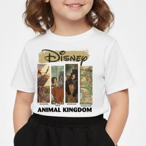 Peut inclure: T-shirt blanc avec le logo Disney au-dessus de quatre panneaux rectangulaires avec des illustrations de "Le Roi Lion", "Tarzan", "Fr&egrave;re des ours" et "Le Livre de la Jungle". Le texte "ANIMAL KINGDOM" est imprim&eacute; en dessous.