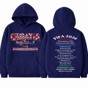 以下が含まれることがあります： 紺色のフーディー。赤と白で「CROATIA」、サッカー選手、そして「WORLD CUP 2026」と書かれています。背面には「FIFA 2026」とカナダ、アメリカ、メキシコの開催都市が記載されています。快適なフード付きスウェットシャツ。