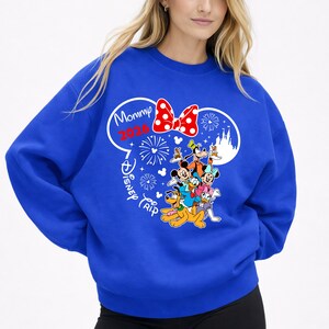 May include: Royal blue sweatshirt featuring a graphic of Disney characters, including Mickey Mouse, Minnie Mouse, and Goofy. The design includes a red polka dot bow, fireworks, and the text "Mommy 2020 Disney Trip."