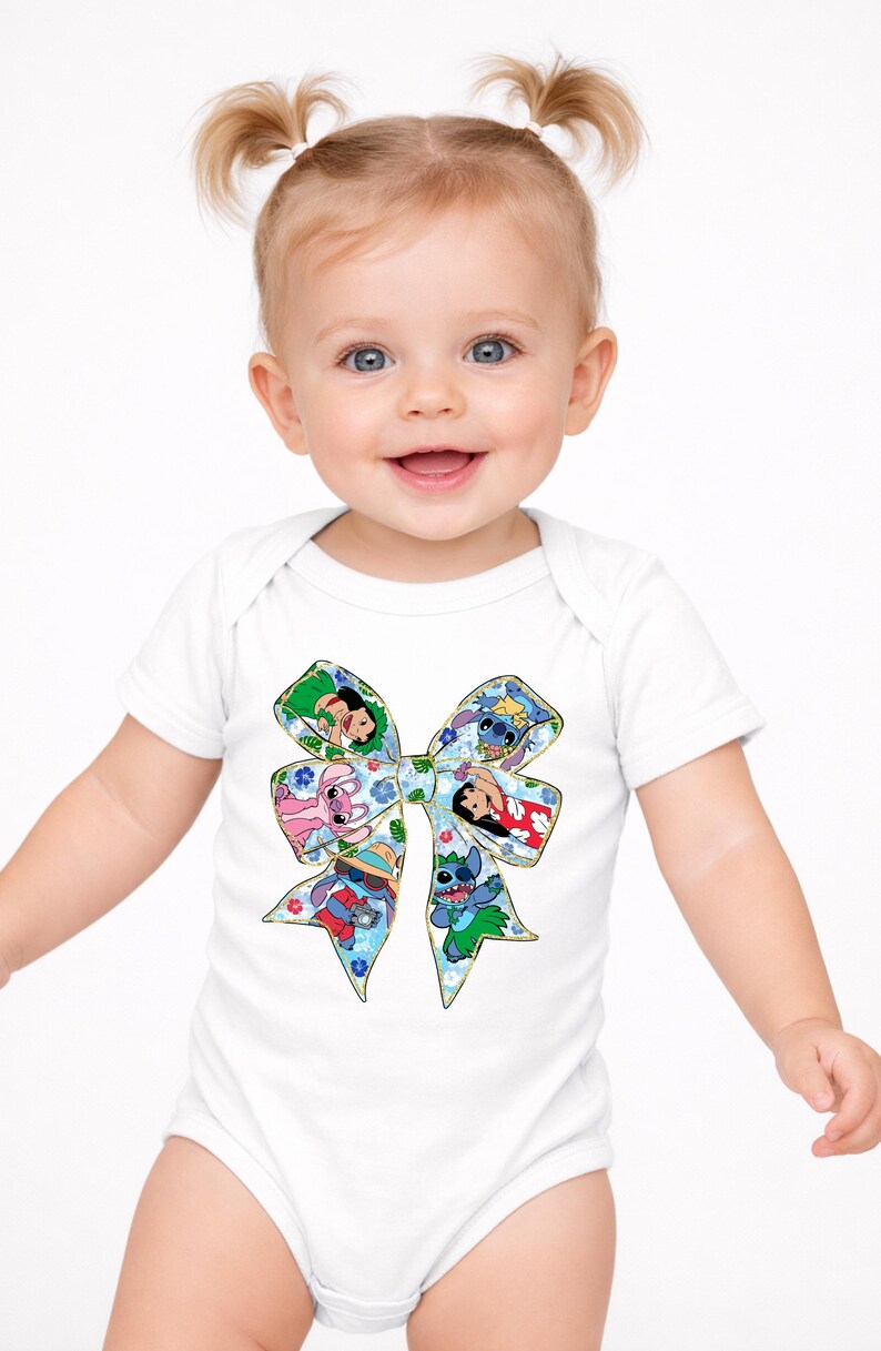 May include: White baby bodysuit with a colourful bow design featuring cartoon characters. The bow is filled with images of characters in a floral pattern. The baby is smiling and has blonde pigtails.