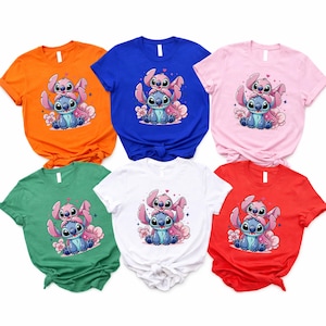 Pode incluir: Seis camisetas de manga curta em v&aacute;rias cores: laranja, azul, rosa, verde, branco e vermelho. Cada camisa apresenta uma ilustra&ccedil;&atilde;o de desenho animado de dois personagens, um azul e outro rosa, com flores.