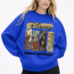 Peut inclure: Sweat-shirt bleu roi avec le logo Disney au-dessus d'un graphisme rectangulaire repr&eacute;sentant des sc&egrave;nes d'Animal Kingdom de Disney. Le graphisme comprend des images du Roi Lion et du Livre de la Jungle. Les mots "ANIMAL KINGDOM" sont imprim&eacute;s en noir.