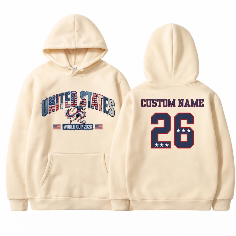 Peut inclure: Sweat &agrave; capuche cr&egrave;me avec l'inscription "UNITED STATES WORLD CUP 2026" en bleu et rouge sur le devant. Le dos affiche "CUSTOM NAME" au-dessus du num&eacute;ro "26" en bleu marine avec une bordure rouge et trois &eacute;toiles.