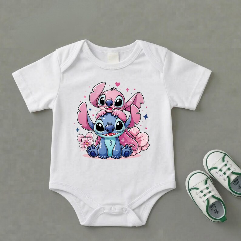Pode incluir: Body de beb&eacute; branco com uma ilustra&ccedil;&atilde;o de desenho animado de duas personagens, uma azul e outra rosa, rodeadas por flores e cora&ccedil;&otilde;es. O conjunto &eacute; completado com sapatos de beb&eacute; brancos e verdes, oferecendo um visual alegre.