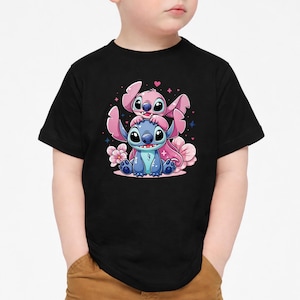 Pode incluir: T-shirt preto com uma ilustra&ccedil;&atilde;o de desenho animado de duas personagens, uma azul e outra rosa, com olhos grandes. O design inclui flores e estrelas cor-de-rosa.