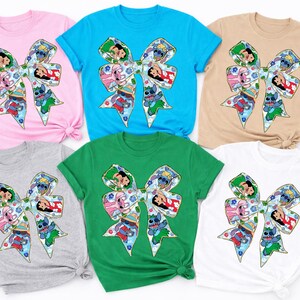 May include: Six short-sleeved t-shirts in various colours: pink, blue, tan, grey, green, and white. Each shirt features a large bow design with cartoon characters. The bow is decorated with a colourful pattern and character illustrations.